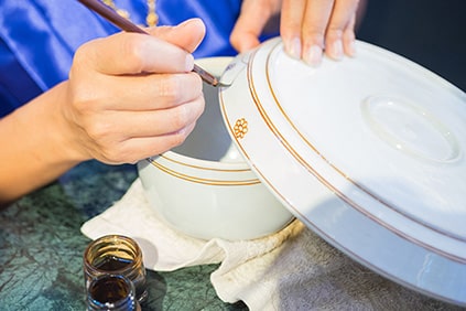 Woman paints on porcelain with brush