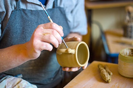 Man works on raw ceramic cup